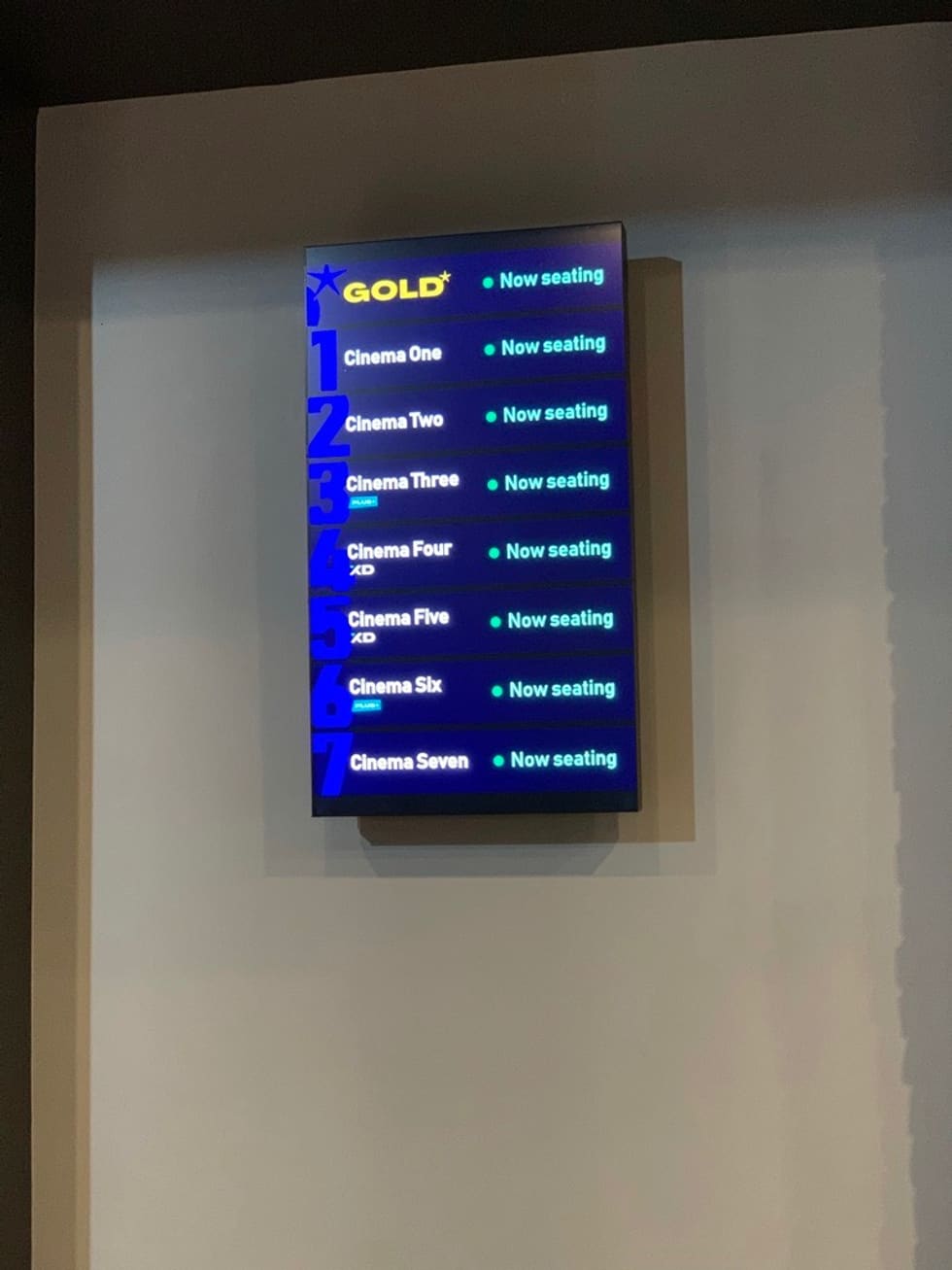 The vertical sign in-situ, on a wall in a cinema lobby.