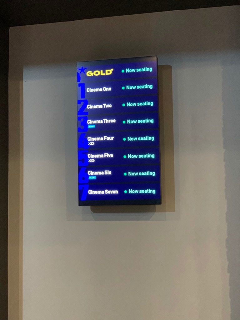 The vertical sign in-situ, on a wall in a cinema lobby.